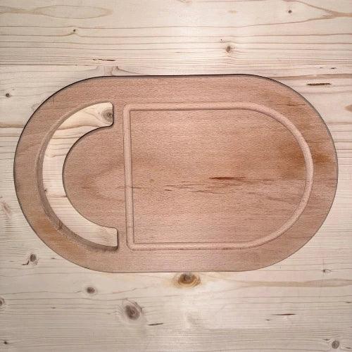 Planche à découper ovale en bois massif avec rigole, posée sur table en bois clair.