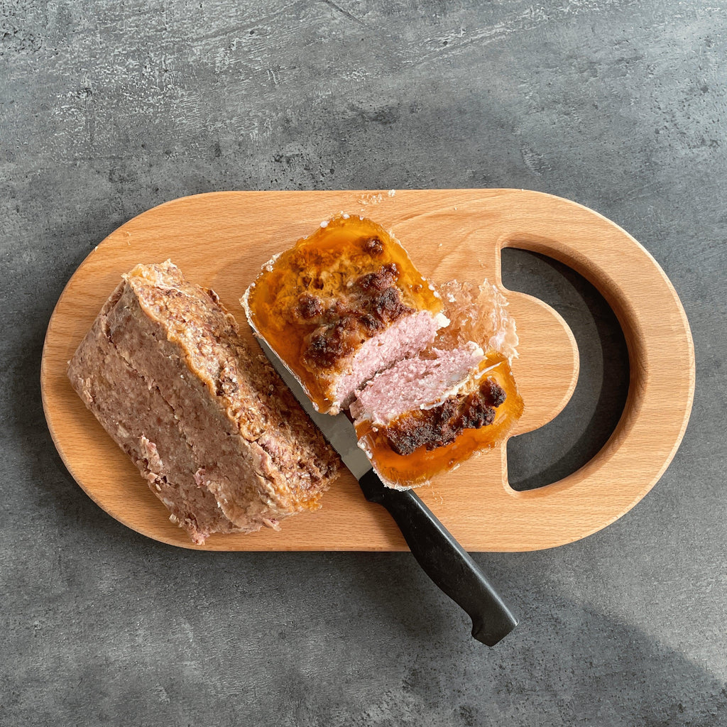 Planche à découper en bois massif avec pâté et couteau sur fond gris