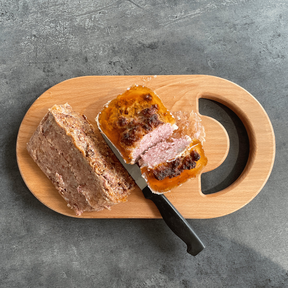 Planche à découper en bois massif avec pâté et couteau sur fond gris