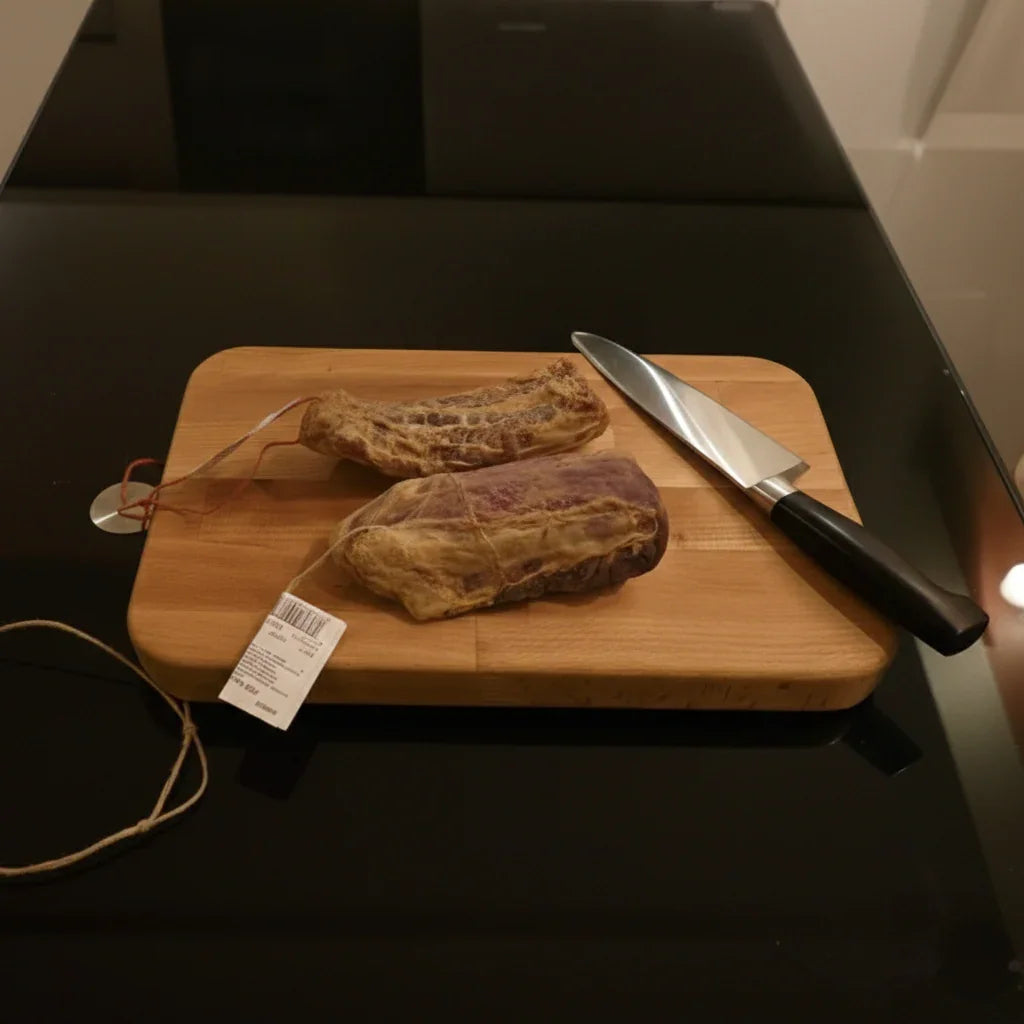 Planche à découper en bois massif avec couteau et charcuterie sur table noire