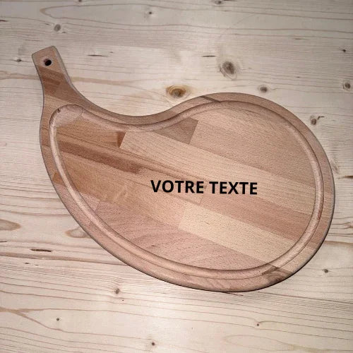 Planche à découper en bois massif en forme de goutte, personnalisable, posée sur une table en bois.